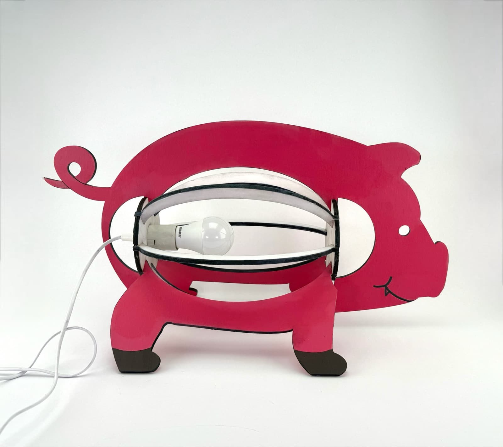 Pink pig-shaped handmade lamp with a curled tail and an exposed bulb held inside a curved frame, front view