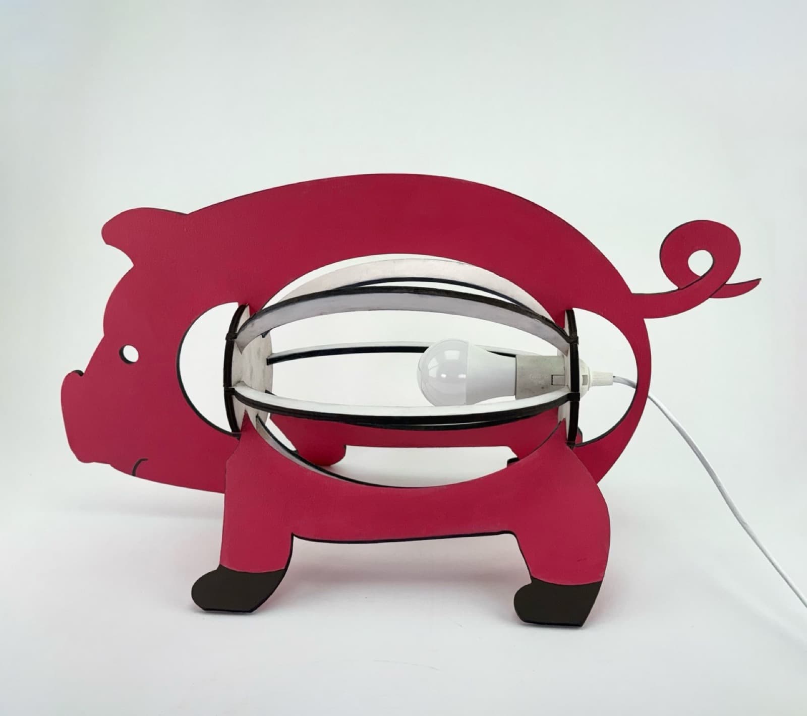 Pig lamp viewed from its other side, with the bulb visible inside the curved frame